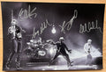 An autographed poster of the rock band U2. Signed photo of Bono, The Edge, Adam Clayton and Larry Mullen Jr in silver ink marker signatures. Photograph autographs for sale on 8x12 inch picture.