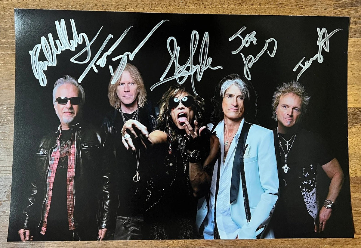 an autographed photo poster of the rock band Aerosmith. Signed photograph of Steven Tyler, Tom Hamilton, Joe Perry, Brad Whitford and Joey Kramer in silver ink marker signatures. Photograph Steven Tyler autographs for sale on picture.