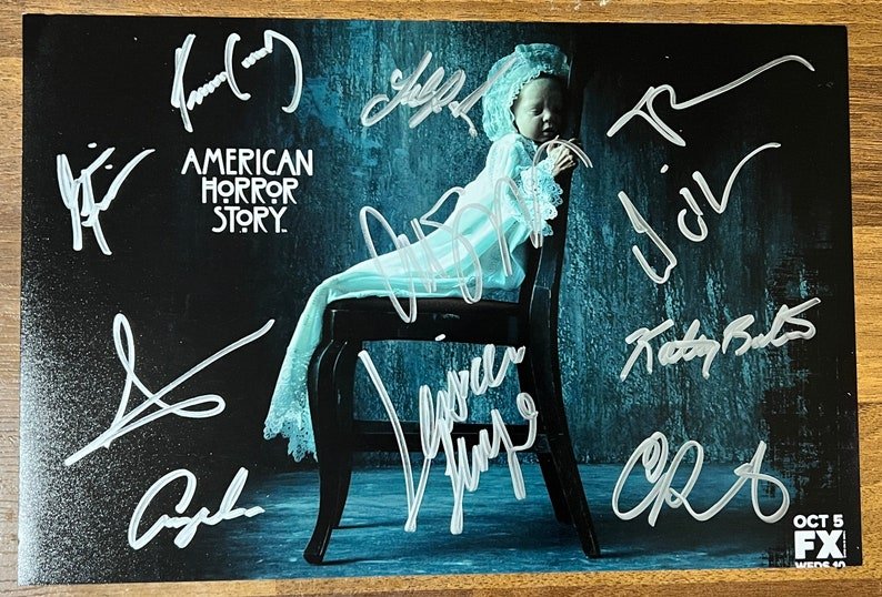 A cast autographed poster of the television series, American Horror Story. Signed photo of Evan Peters, Sarah Paulson, Denis O'Hare, Jessica Lange, Frances Conroy, Kathy Bates, Angela Bassett, Lily Rabe, Emma Roberts, Taissa Farmiga and Chloe Sevigny in silver ink markers signatures. Photograph autographs for sale on 8x12 inch picture.