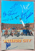 A cast autographed photo poster of the film 'Asteroid City'. Signed photo of Jason Schwartzman, Scarlett Johansson, Tom Hanks, Bryan Cranston, Jeffrey Wright, Edward Norton, Tilda Swinton and Adrien Brody in blue silver and black ink marker signatures. phtograph Asteroid City autographs for sale on picture.