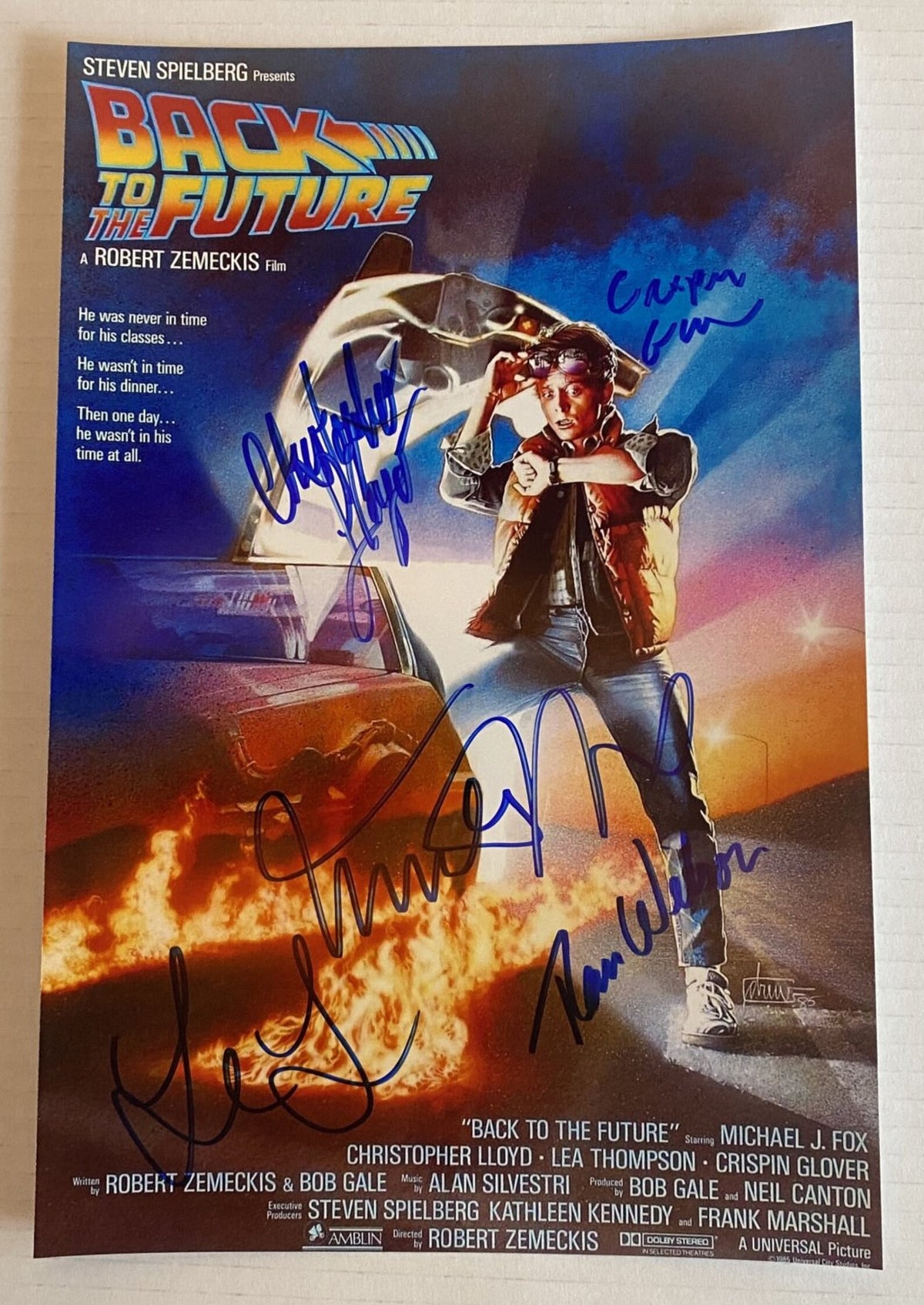 A cast autographed 'Back to the Future' movie poster. Signed photo of Michael J. Fox, Christopher Lloyd, Lea Thompson, Tom Wilson and Crispin Glover in blue ink marker signatures. Photograph autographs for sale on 8x12 inch picture.