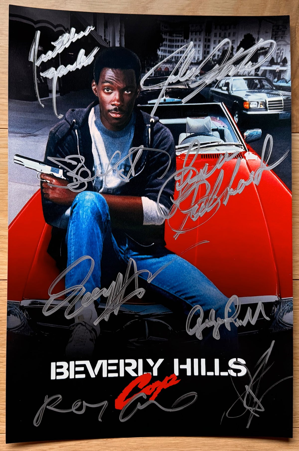 A cast autographed Beverly Hills Cop poster. Signed photo of Eddie Murphy, Judge Reinhold, Ronny Cox, John Ashton, Lisa Eilbacher, Steven Berkoff, James Russo and Jonathan Banks in silver ink marker signatures. Photograph autographs for sale on 8x12 inch picture.