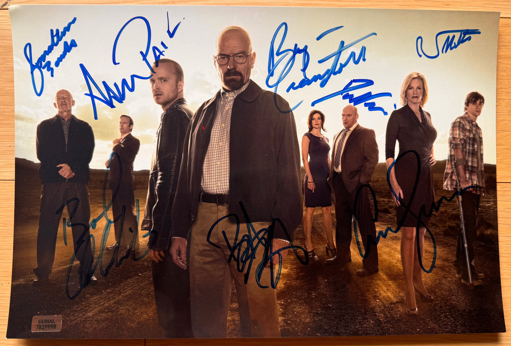 A cast autographed photo poster from the AMC television series, Breaking Bad. Signed photo of Bryan Cranston, Aaron Paul, Bob Odenkirk, Anna Gunn, Dean Norris, Betsy Brandt, Jonathan Banks and RJ Mitte in blue ink marker signatures. Photograph autographs for sale on 8x12 inch picture.