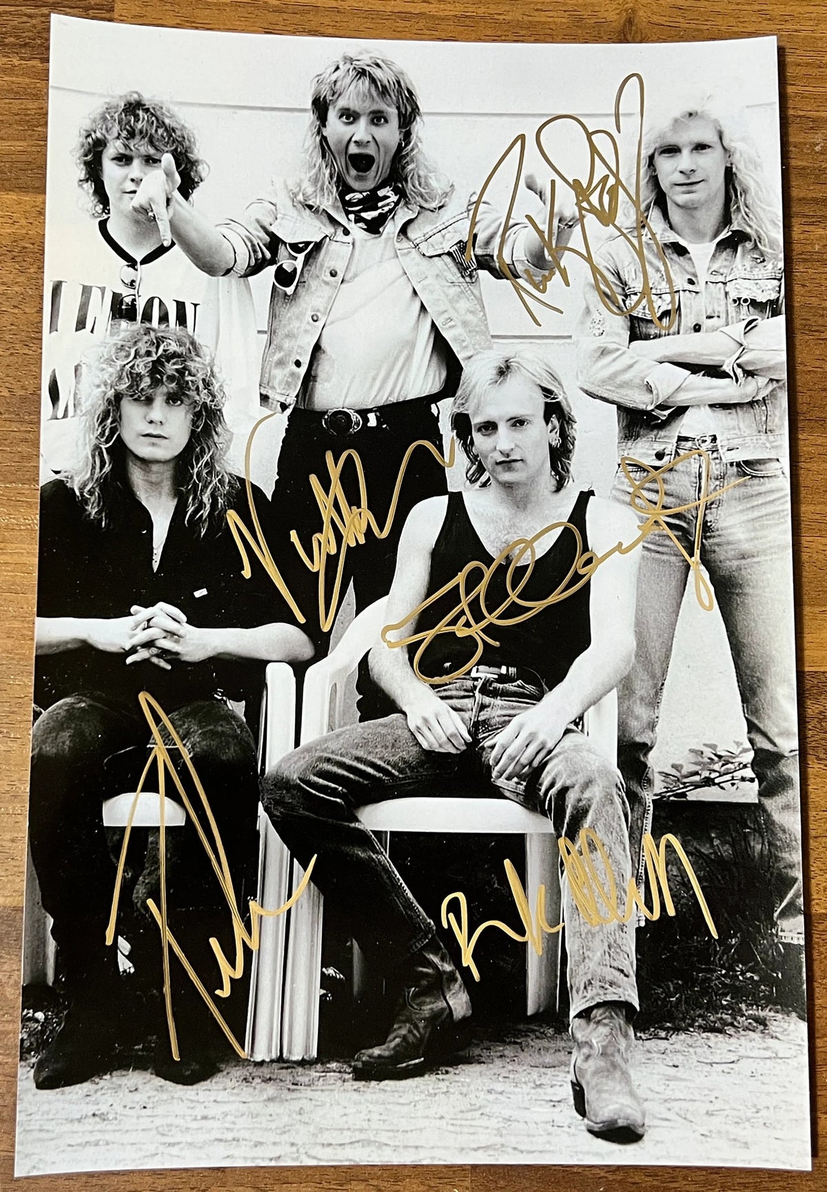 An autographed photo of the band Def Leppard. Signed poster of Joe Elliott, Steve Clark, Rick Savage, Rick Allen and Phil Collen in gold ink markers signatures. Photograph autographs for sale on 8x12 inch picture.