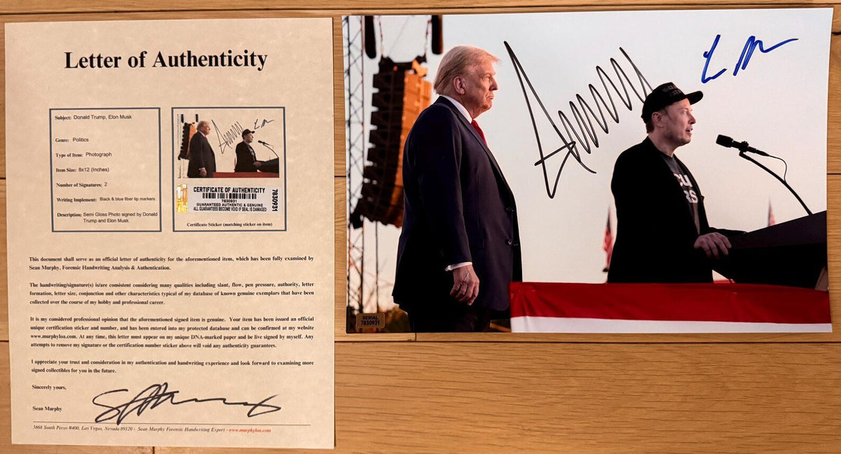 An autographed 8x12 photograph of Donald Trump and Elon Musk at a rally, signed in black and blue ink, displayed on a wooden surface with COA.
