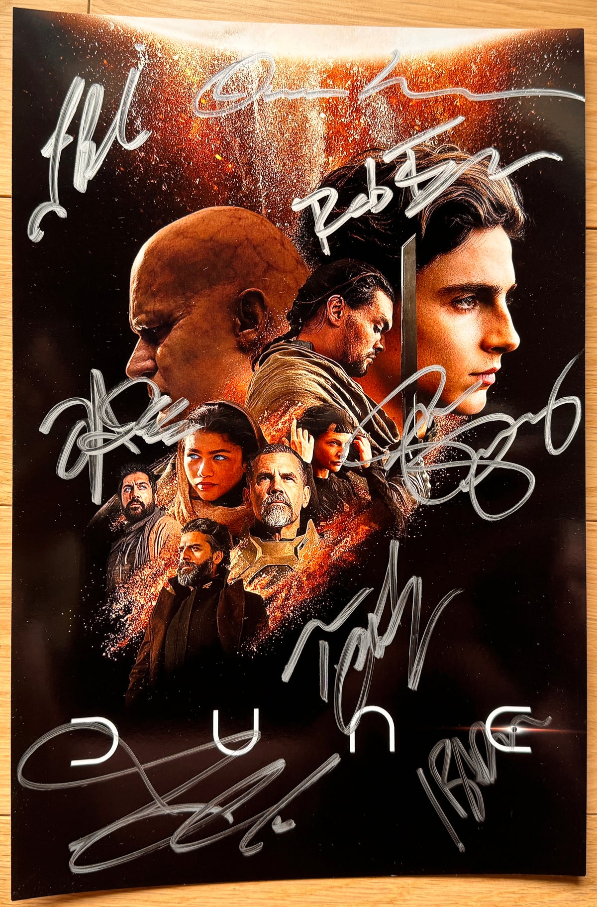 A cast autographed 'Dune' 2001 movie poster. Signed photo of Timothee Chalamet, Zendaya, Josh Brolin, Jason Momoa, Stellan Skarsgard, Rebecca Ferguson, Oscar Isaac and Javier Bardem in silver ink marker signatures. Photograph autographs for sale on 8x12 inch picture.