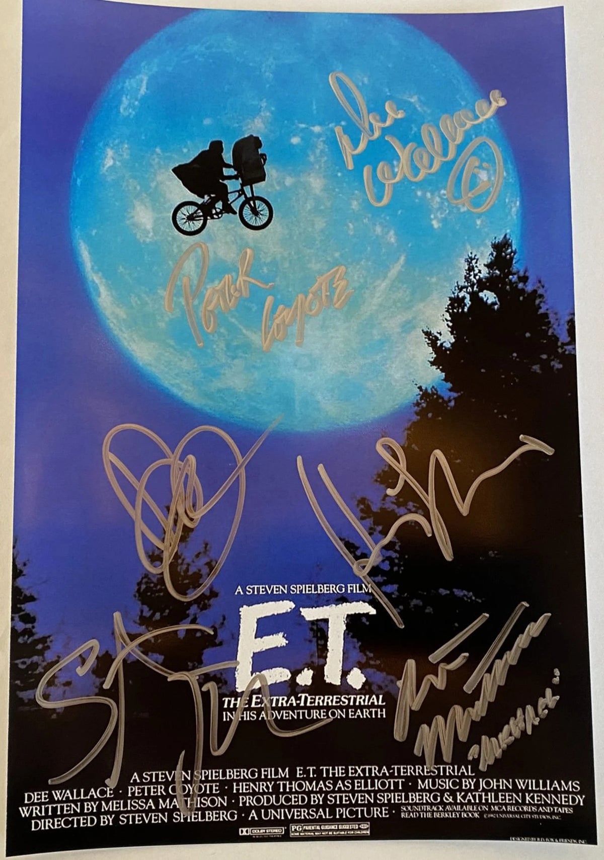 A cast autographed photo poster of the movie E.T. Signed photo of Henry Thomas, Drew Barrymore, Dee Wallace, Michael MacNaughton, Peter Coyote and Steven Spielberg in silver ink marker signatures. Photograph autographs for sale on 8x12 inch picture.