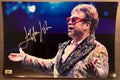 An autographed photo poster of the pop rock star musician, Elton John. Signed photograph in silver ink marker signatures. Photograph Elton John autographs for sale on 8x12 inch picture.