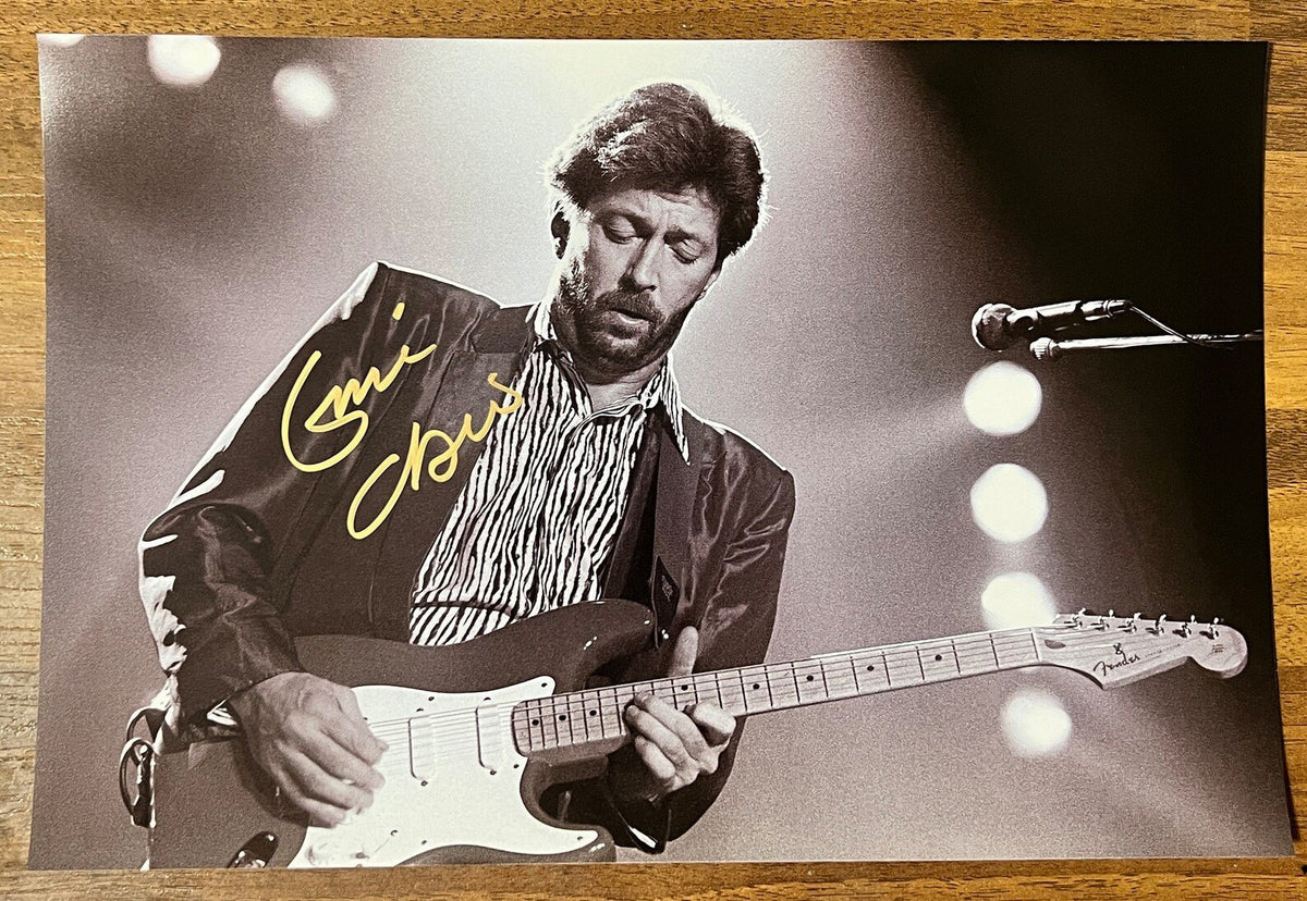 A signed black and white photograph of rock singer, Eric Clapton. autographed  photo poster in gold ink marker signatures. photograph Eric Clapton autographs for sale on 8x12 inch picture.