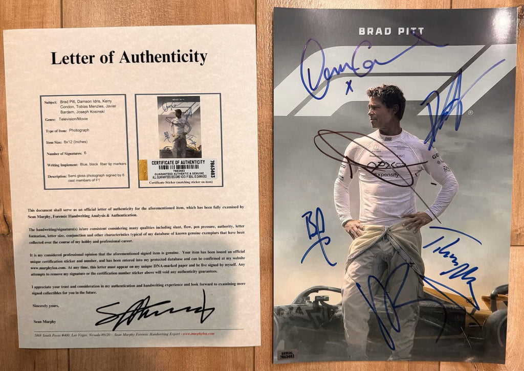 An autographed 8x12 photo print of Brad Pitt as Dominic Toretto from the movie F1 signed in blue, and black ink, displayed on a wooden surface with COA.