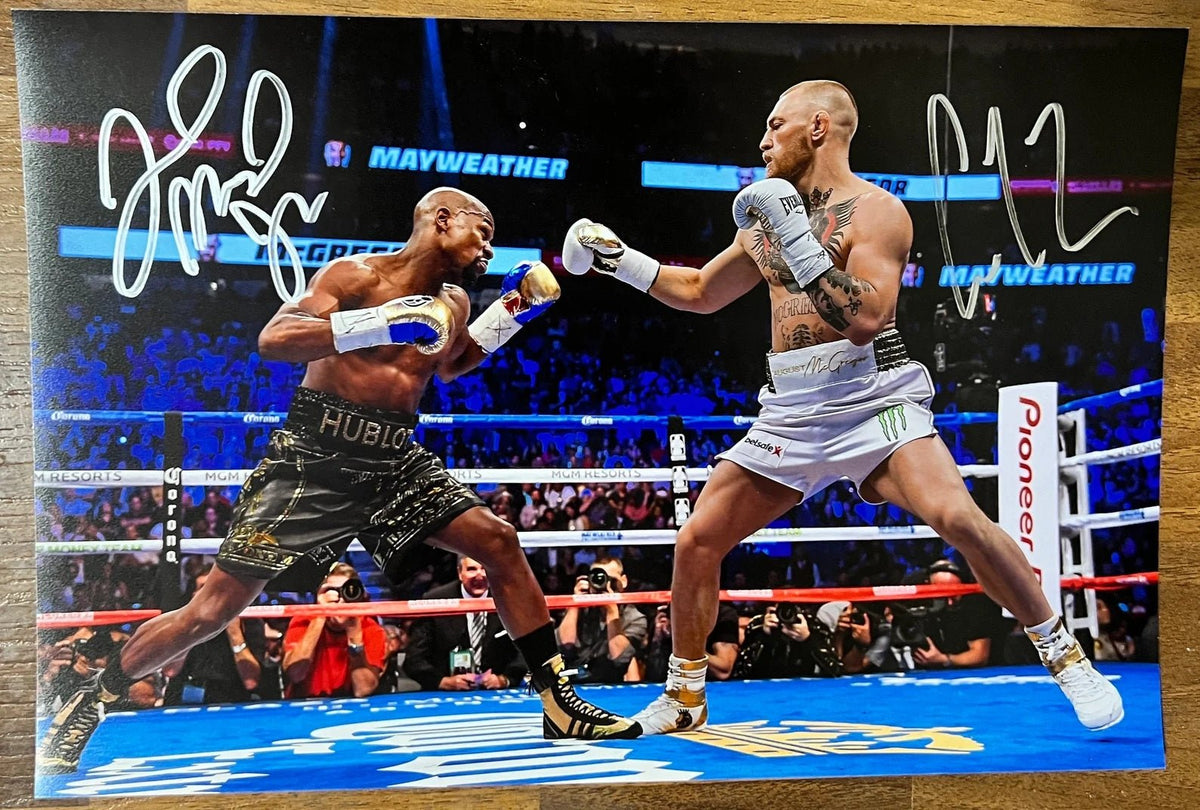 An autographed photo poster of MMA and boxer fighters, Floyd Mayweather Jr and Connor McGregor. Signed photo in silver ink signatures. Photograph autographs Connor McGregor autographs for sale on 8x12 inch picture.