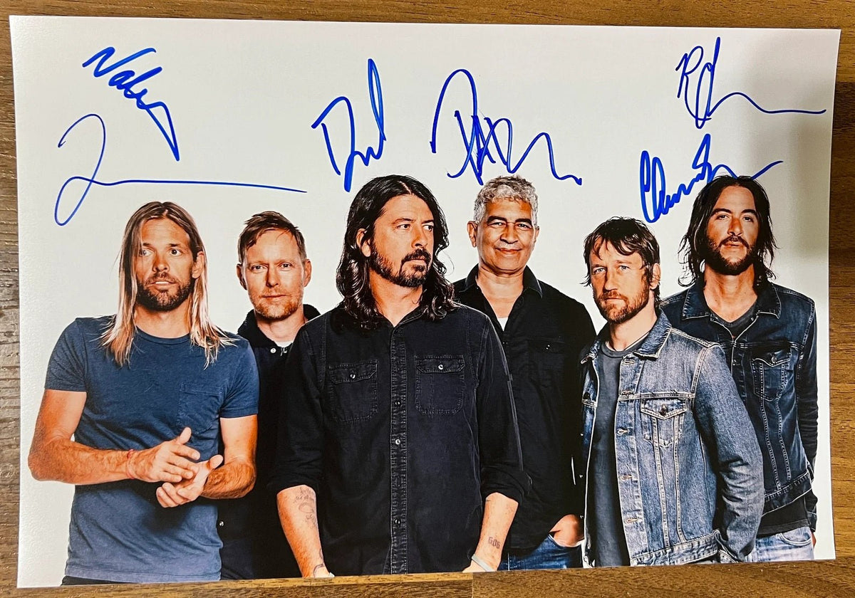 An autographed poster of the rock band, Foo Fighters. Signed photo of Dave Grohl, Pat Smear, Nate Mendel, Taylor Hawkins, Chris Shiflett and Rami Jaffee in blue ink marker signatures. Photograph autographs for sale on 8x12 inch picture.