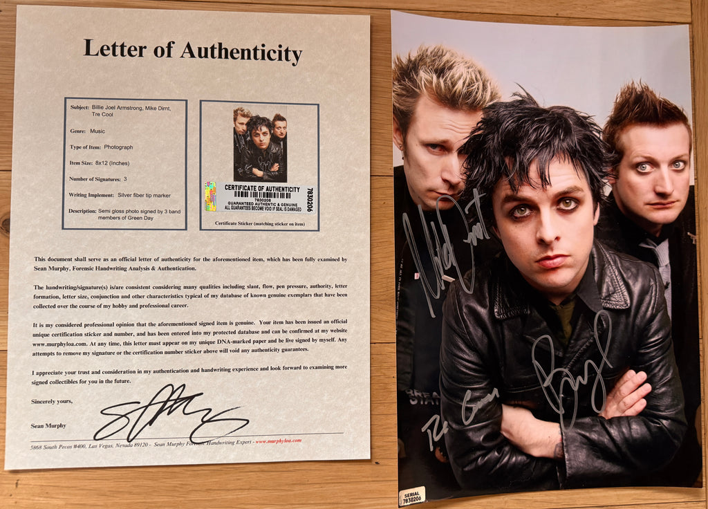 An autographed 8x12 photo print of the band Green Day, featuring the three members in their signature style with signatures in silver ink across the front with COA.