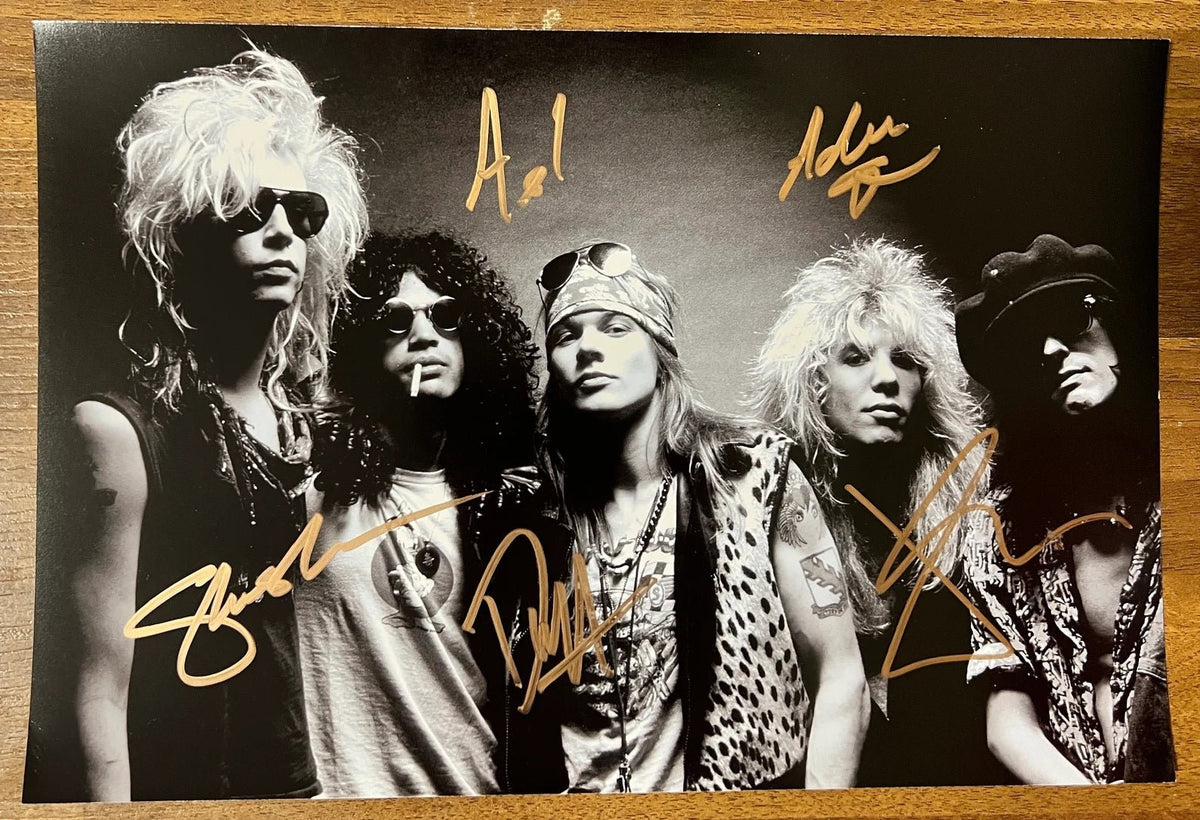 An autographed poster of the heavy metal band, Guns N Roses. Signed photo of Axl Rose, Slash, Duff McKagan, Izzy Stradlin and Steven Adler in gold ink marker signatures. Photograph autographs for sale on 8x12 inch picture.