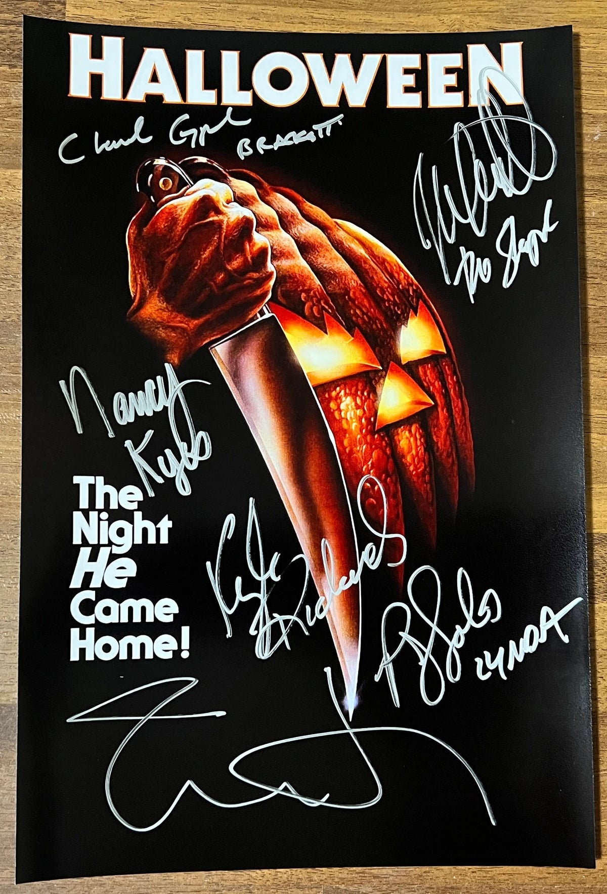 A cast signed collectible poster of Michael Myers from the 1978 movie Halloween. Signed photo of Jamie Lee Curtis, Nick Castle, Nancy Kyes, P.J. Soles, Charles Cyphers and Kyle Richards in silver ink marker signatures. Photograph autographs for sale on 8x12 inch picture.