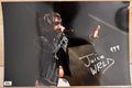 An autographed 8x10 photograph of rapper Juice WRLD performing on stage, signed in silver marker with the number 999. The photo shows him wearing sunglasses and a black jacket, with a small authentication label in the bottom-left corner. Photograph autographs for sale on 8x12 inch picture.