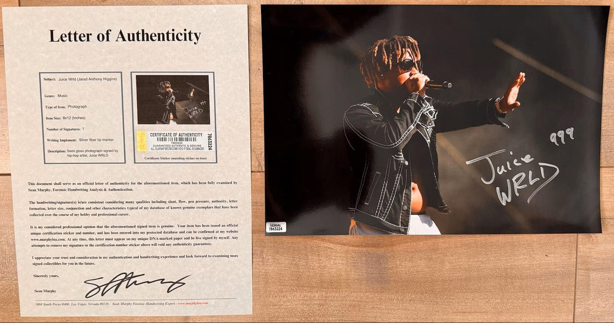 An autographed 8x10 photograph of rapper Juice WRLD performing on stage, signed in silver marker with the number 999. The photo shows him wearing sunglasses and a black jacket, with a small authentication label in the bottom-left corner with COA.