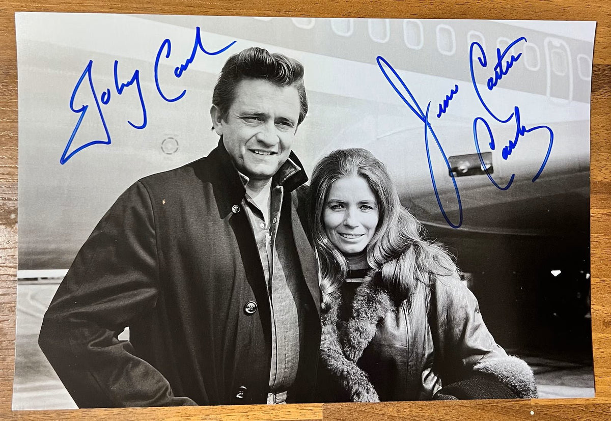 an autographed photo poster of Johnny Cash and his wife June Carter Cash. signed photo in blue ink markers signatures. photograph Johnny Cash autographs for sale on an 8x12 inch picture.