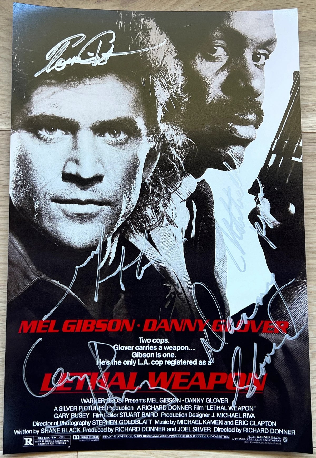 A cast autographed poster of the movie Lethal Weapon. Signed photo of Mel Gibson, Danny Glover, Gary Busey, Mitchell Ryan and Tom Atkins in silver ink marker signatures. Photograph autographs for sale on 8x12 inch picture.