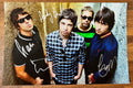 An autographed poster of the band Oasis. Signed photo of Liam Gallagher, Noel Gallagher, Gem Archer and Andy Bell in silver ink markers signatures. Photograph autographs for sale on 8x12 inch picture.