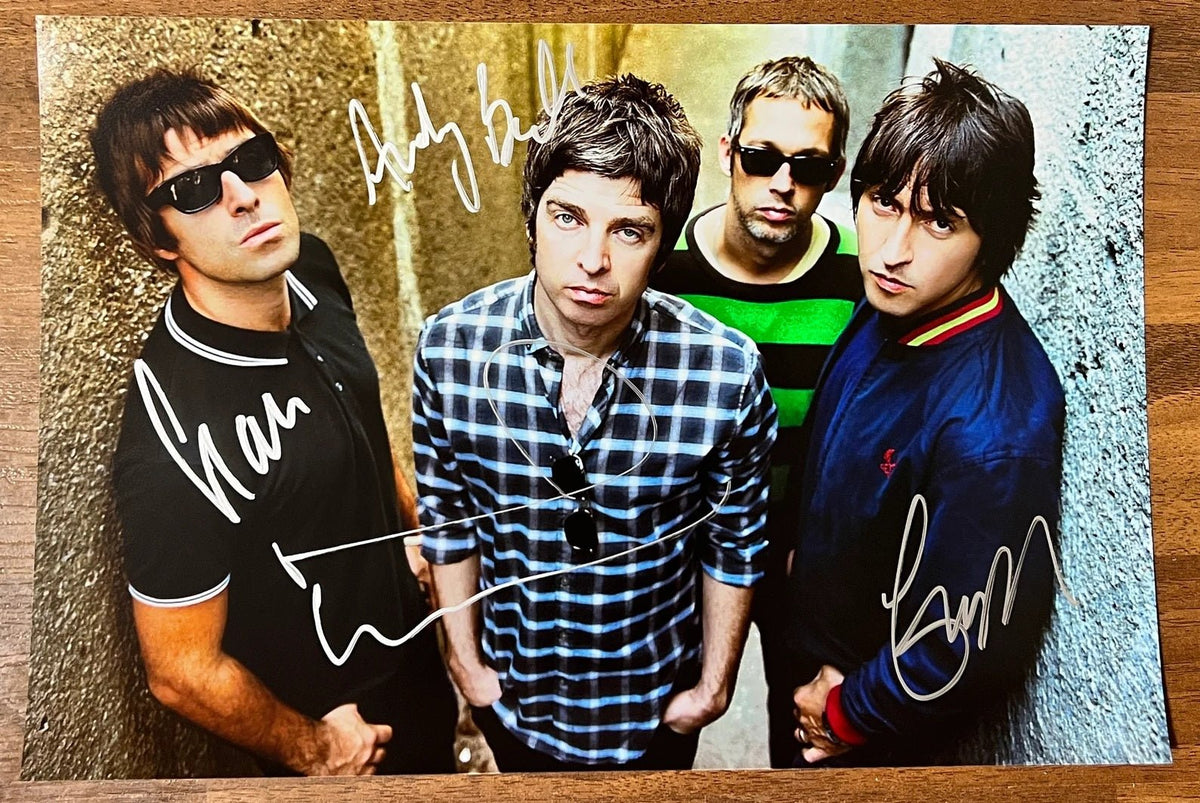 An autographed poster of the band Oasis. Signed photo of Liam Gallagher, Noel Gallagher, Gem Archer and Andy Bell in silver ink markers signatures. Photograph autographs for sale on 8x12 inch picture.