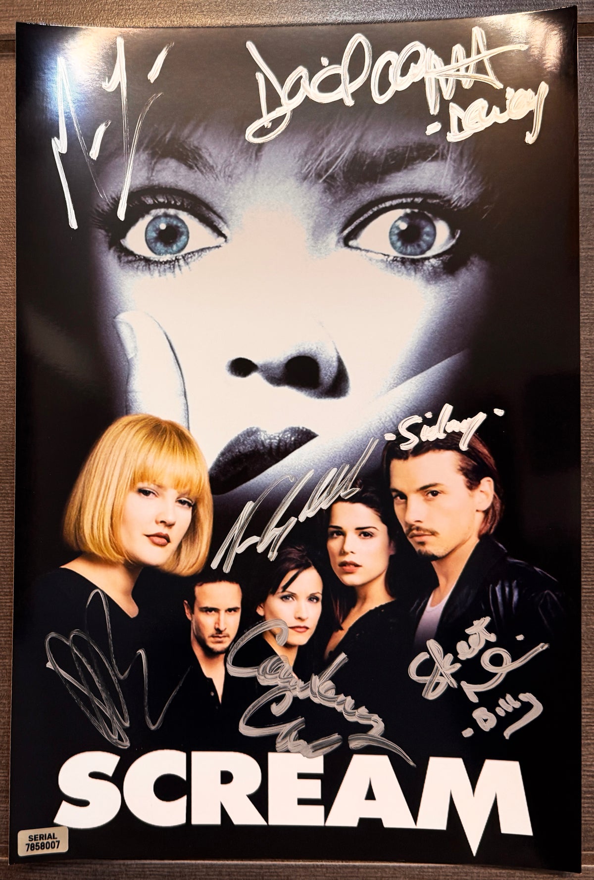 A cast autographed Scream movie poster. Signed photo of Neve Campbell, Skeet Ulrich, Courteney Cox, Drew Barrymore, David Arquette and Matthew Lillard in silver ink marker signatures. Photograph autographs for sale on 8x12 inch picture.