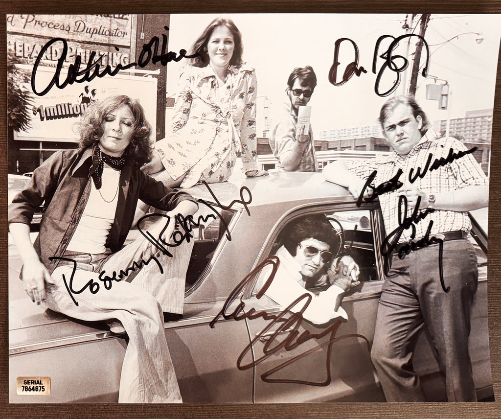 A cast autographed poster of the original SCTV actors. Signed photo of John Candy, Catherine O'Hara, Eugene Levy, Dan Aykroyd and Rosemary Radcliffe in black ink marker signatures. Photograph John Candy autographs for sale on 8x12 inch picture.