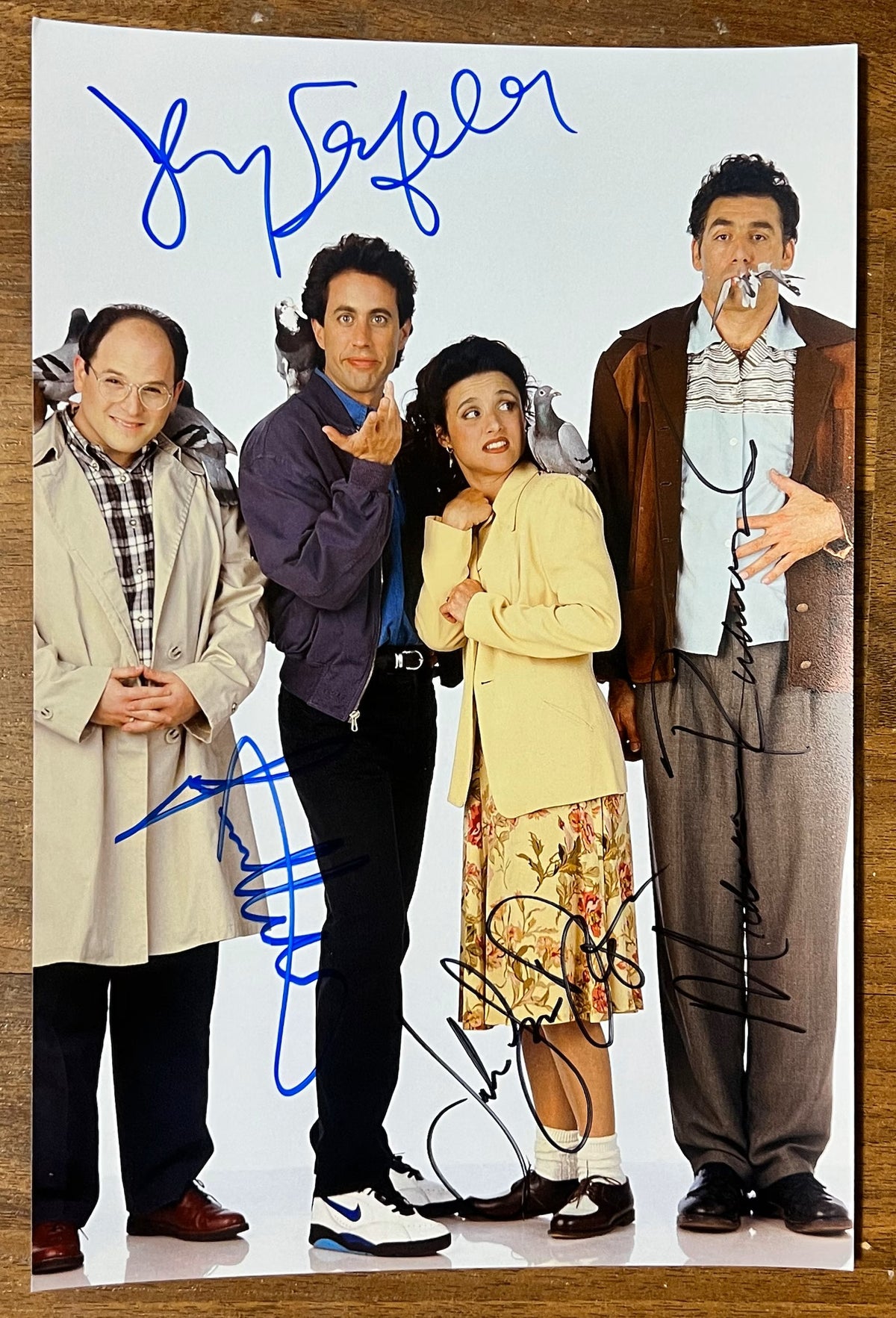 A cast autographed photo of the sitcom series, Seinfeld. Signed poster by Jerry Seinfeld, Michael Richards, Jason Alexander and Julia Louis-Dreyfus in blue and black ink markers signatures. photograph Sinefeld autographs for sale on  8x12 inch picture.