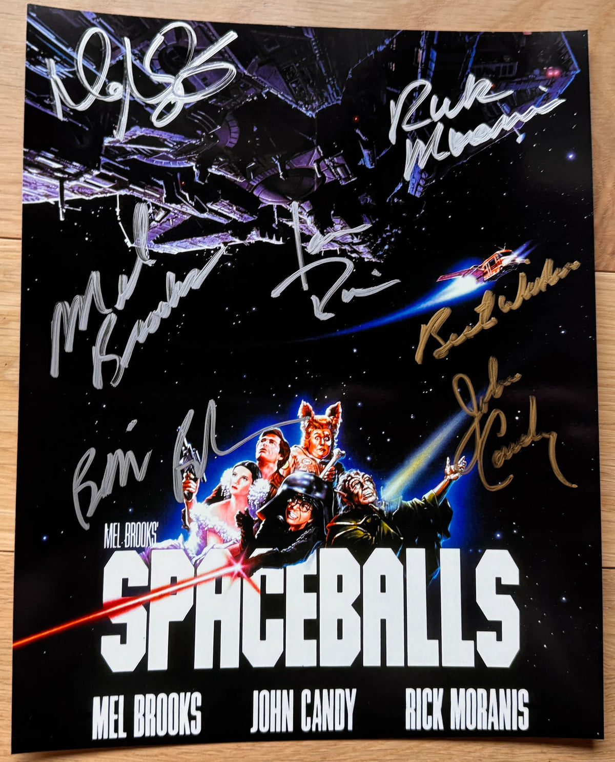 A cast autographed poster for the movie Spaceballs. Signed photo of John Candy, Mel Brooks, Bill Pullman, Rick Moranis, Daphne Zuniga and Joan Rivers in gold and silver ink marker signatures. Photograph autographs for sale on 8x12 inch picture.