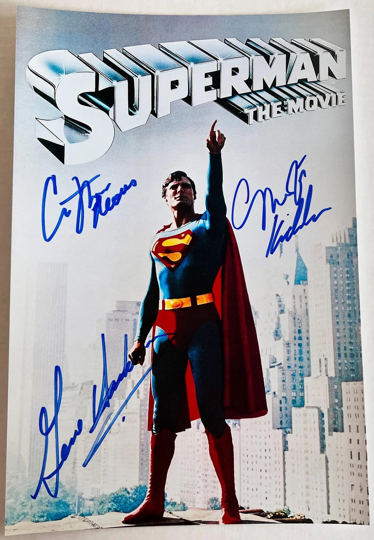 A cast autographe poster of the 1978 superhero movie, Superman The Movie. Signed photo of Christopher Reeve, Gene Hackman and Margot Kidder in blue ink marker signatures. Photograph autographs for sale on 8x12 inch picture.