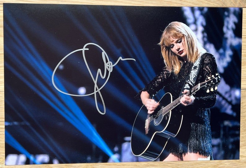 An autographed photo print of Taylor Swift performing on stage. Signed poster in silver ink marker signatures. Photograph autographs for sale on 8x12 in picture. 