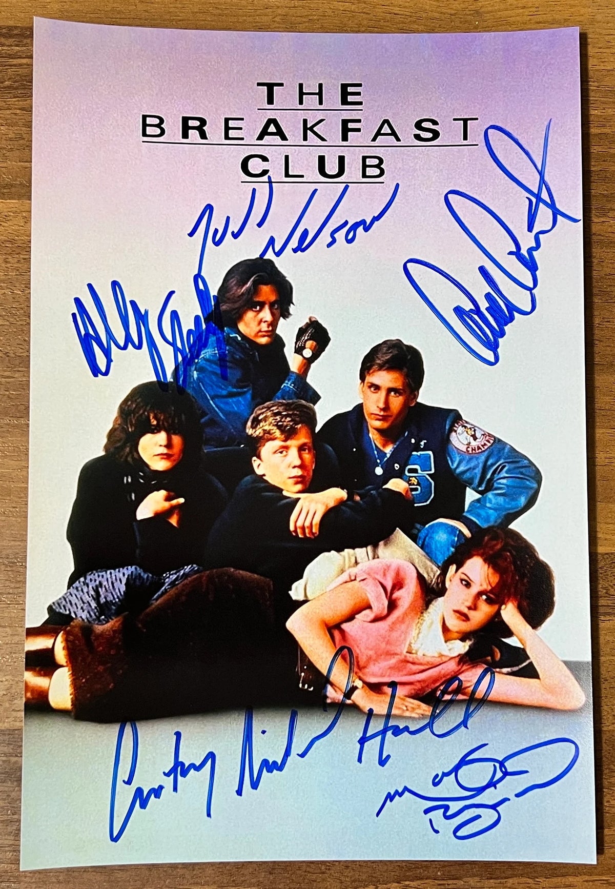 a cast autographed poster of movie, The Breakfast Club. Signed photograph by actors Judd Nelson, Anthony Michael Hall, Molly Ringwald, Ally Sheedy and Emilio Estevez in blue ink signatures. Photo is 8x12 inches in size. The Breakfast Club autographs for sale.