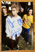 an autographed photo of the band The Deftones. autographed poster by Chino Moreno, Chi Cheng, Stephen Carpenter and Abe Cunningham in blue ink on an 8x12 inch poster photograph autographs for sale.