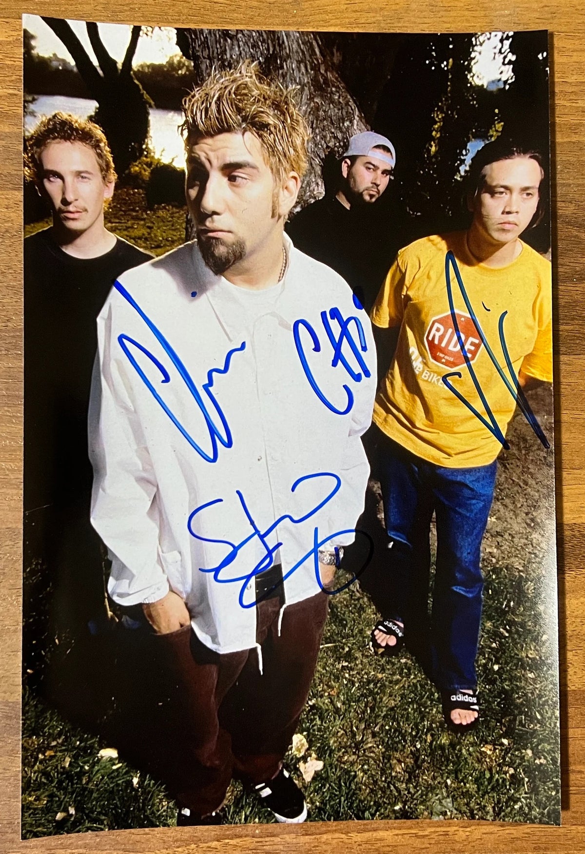 an autographed photo of the band The Deftones. autographed poster by Chino Moreno, Chi Cheng, Stephen Carpenter and Abe Cunningham in blue ink on an 8x12 inch poster photograph autographs for sale.