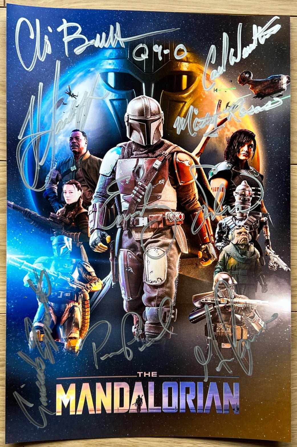 A cast autographed poster of Disney's television series, The Mandalorian. Signed photo of Pedro Pascal, Chris Bartlett, Katee Sackhoff, Carl Weathers, Giancarlo Esposito, Emily Swallow, Misty Rosas and Gina Carano in silver ink marker signatures. Photograph autographs for sale on 8x12 inch picture.