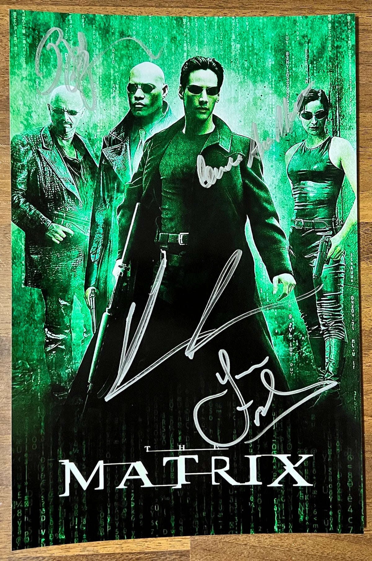 A cast autographed photo poster from the 1999 movie, The Matrix. Signed photo of Keanu Reeves, Laurence Fishburne, Carrie-Anne Moss and Joe Pantoliano in silver ink marker signatures. Photograph The Matrix autographs for sale on 8x12 inch picture.