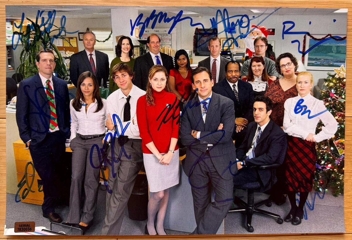 A cast autographed photo poster from the television series, The Office. Signed photo of Steve Carrell. Rainn Wilson, Ed Helms, John Krasinski, Jenna Fischer, B.J. Novak, Melora Hardin, David Denman, Leslie David Baker, Brian Baumgartner and Kate Flannery in blue ink marker signatures. Photograph The Office autographs for sale on 8x12 inch picture.