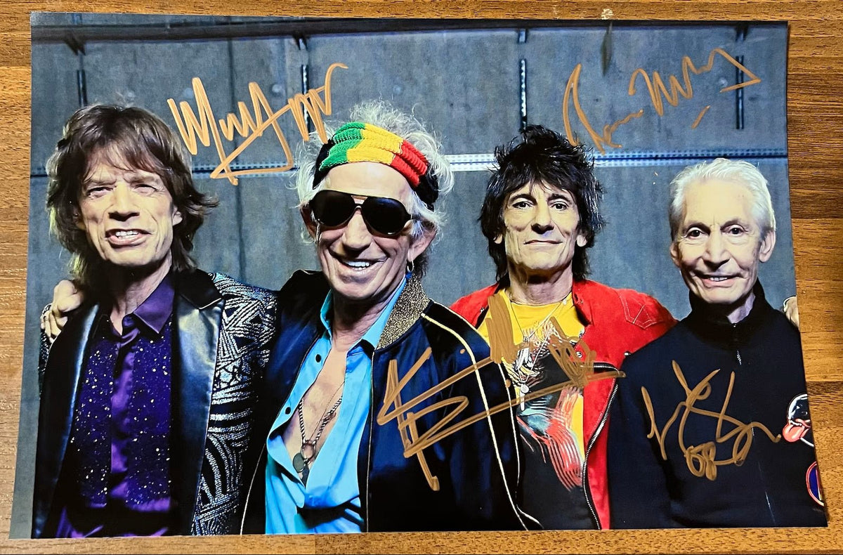 an autographed photo of the band The Rolling Stones. Signed poster of Mick Jagger, Keith Richards, Charlie Watts and Ronnie Wood in gold ink marker signatures. Photograph autographs for sale on 8x12 inch picture.