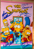 A cast signed 8x12 'The Simpsons' poster. Signed photo of Dan Castellaneta, Nancy Cartwright, Matt Groening, Julie Kavner and Yeardley Smith in blue ink marker signatures. Photograph autographs for sale on 8x12 inch picture.