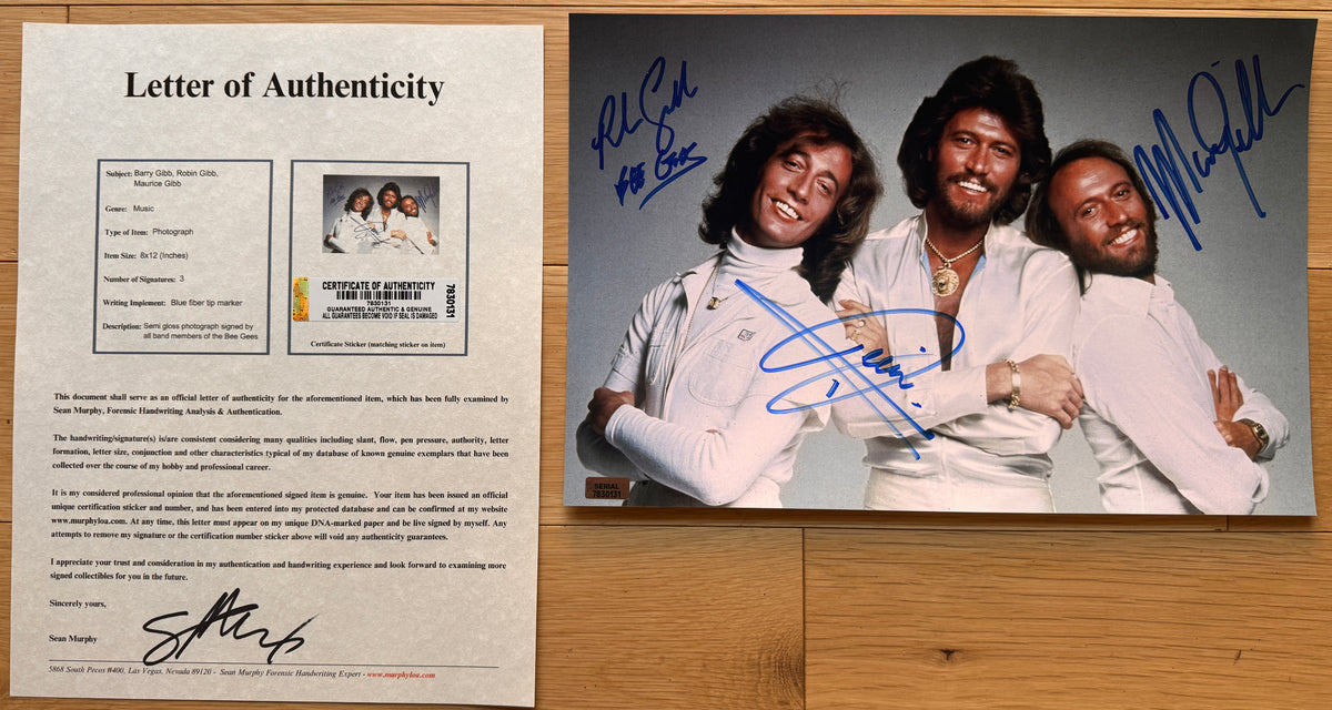 an autographed photo of the band, The Bee Gees. Signed poster by Barry Gibb, Robin Gibb and Maurice Gibb in blue ink markers. photograph autographs for sale with an 8x12 inch picture with COA.