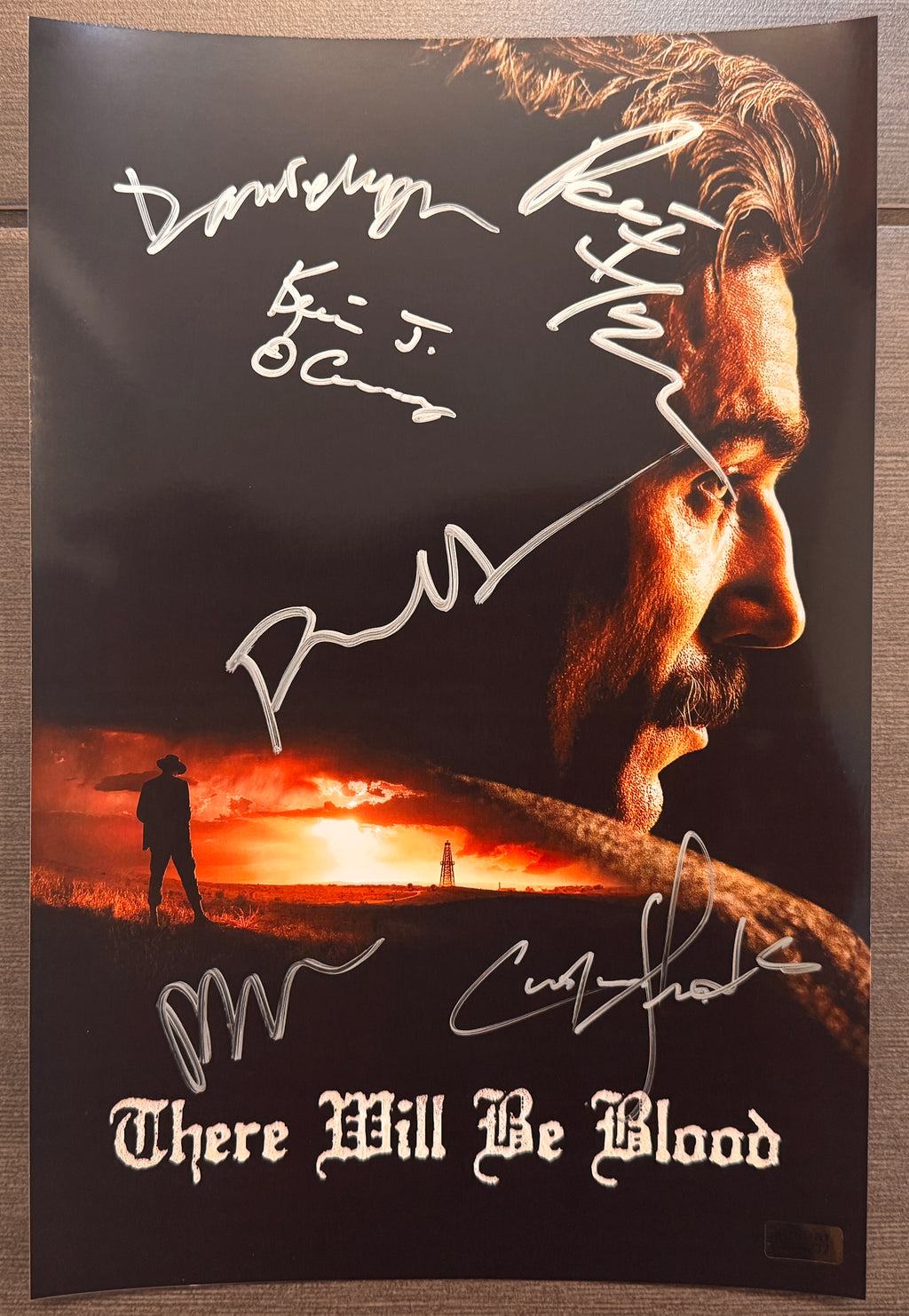 A cast autographed photo poster of the movie, There Will Be Blood. Signed photograph of Daniel Day-Lewis, Paul Dano, Paul Thomas Anderson, Cirian Hinds, Paul F. Tompkins and Kevin J. O'Connor in silver ink marker signatures. Photograph There Will Be Blood autographs for sale on 8x12 inch picture.