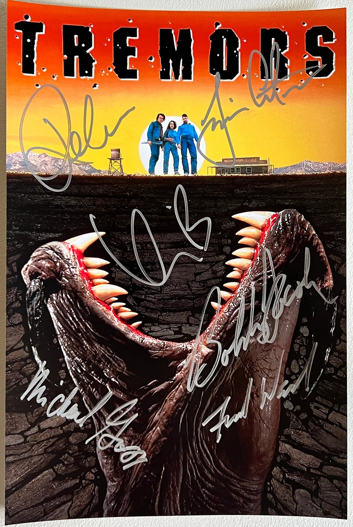 A cast signed 'Tremors' movie poster. Autographed photo by Kevin Bacon, Fred Ward, Finn Carter, Michael Gross, Reba McEntire and Bobby Jacoby in silver ink marker signatures. Photograph autographs for sale on 8x12 inch picture.