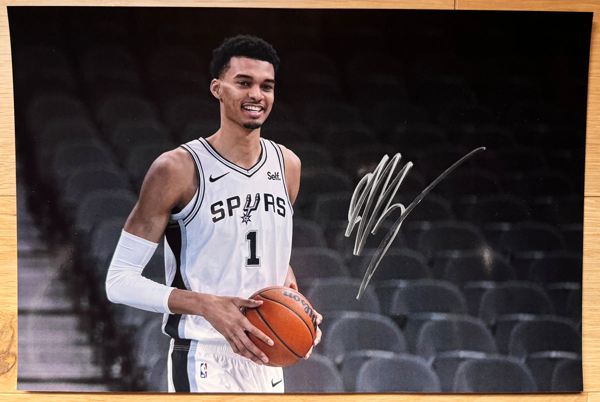 An autographed poster of NBA basketball star, Victor Wembanyama also known as Wemby. Rookie auto signed in silver ink signatures. Topps Fanatics basketball in hand. Photograph Victor Wembanyama autographs for sale on 8x12 inch picture.