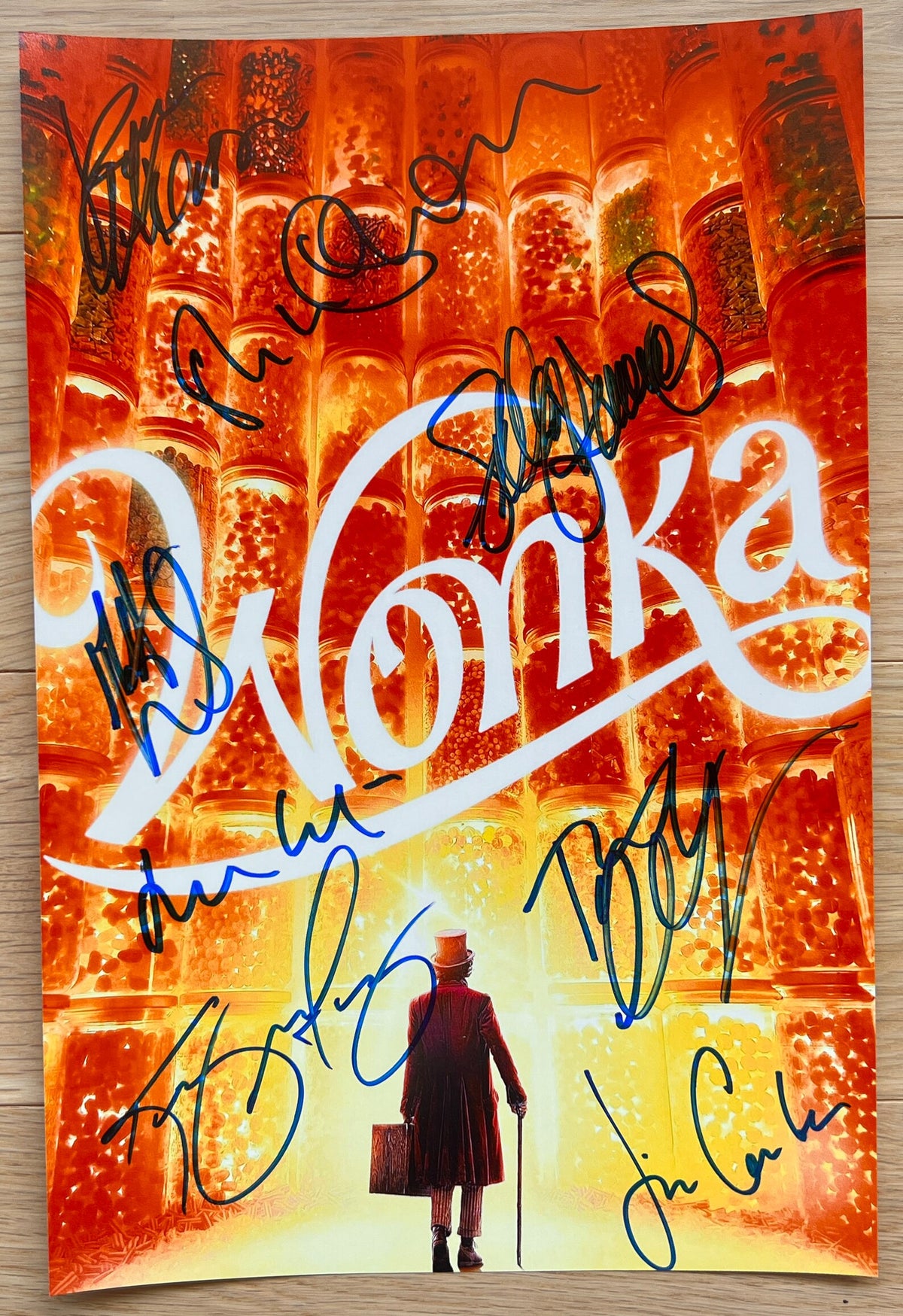 A cast autographed photo poster from the 2023 movie, WONKA. Signed photo of Timothee Chalamet, Olivia Colman, Hugh Grant, Sally Hawkins, Keegan-Michael Key, Rowan Atkinson, Matt Lucas and Jim Carter in blue ink marker signatures. Photograph autographs for sale on 8x12 inch picture.